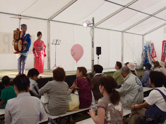 Chindon Tsūshinsha performing in a tent for those who have survived the disaster.