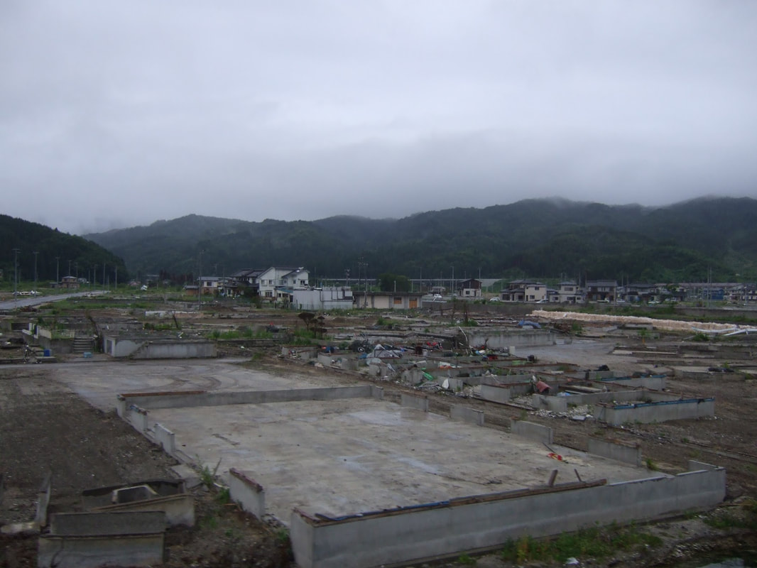 Four months after the tsunami and earthquake 2011, a building foundation sits empty and leveled against a flattened landscape.